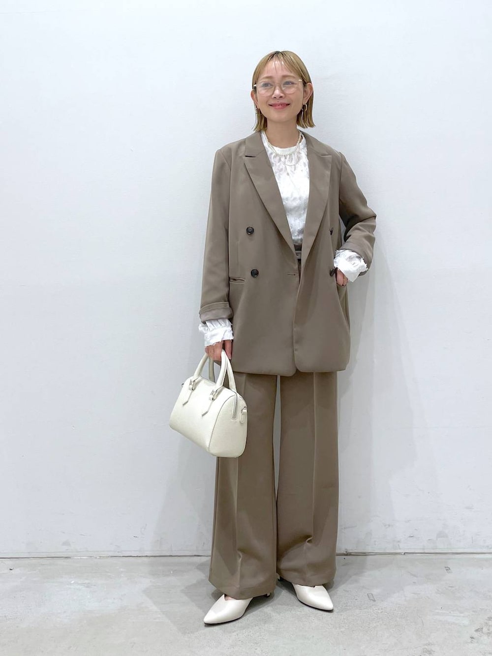 ブラウン系のスーツパンツ、ホワイト系のシャツ/ブラウス、ホワイト系のパンプスを着用したレディースの冬コーディネートの1枚目の写真