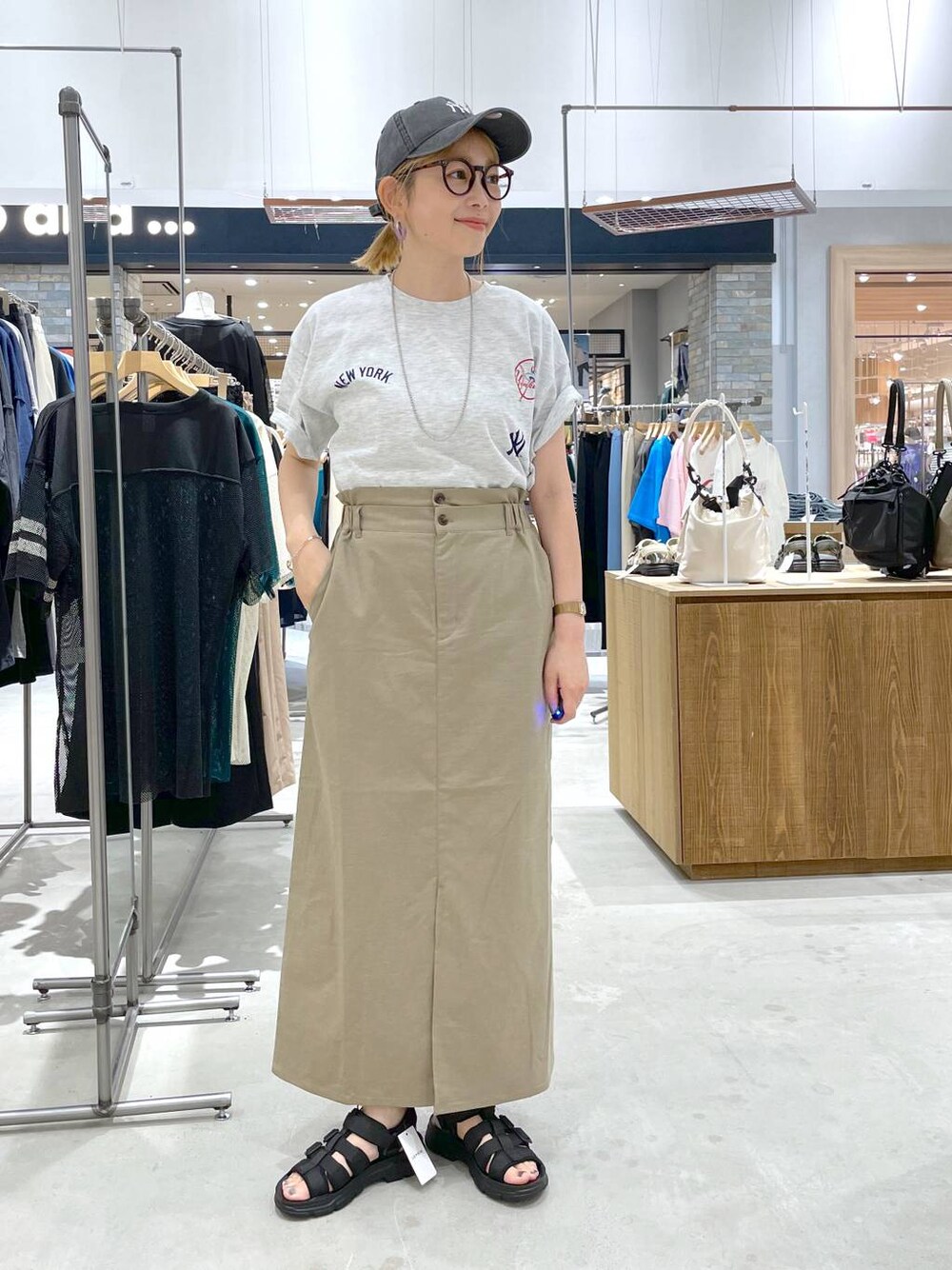 ブラック系のサンダル、ベージュ系のTシャツ/カットソー、グリーン系のスカートを着用したレディースの夏コーディネートの1枚目の写真