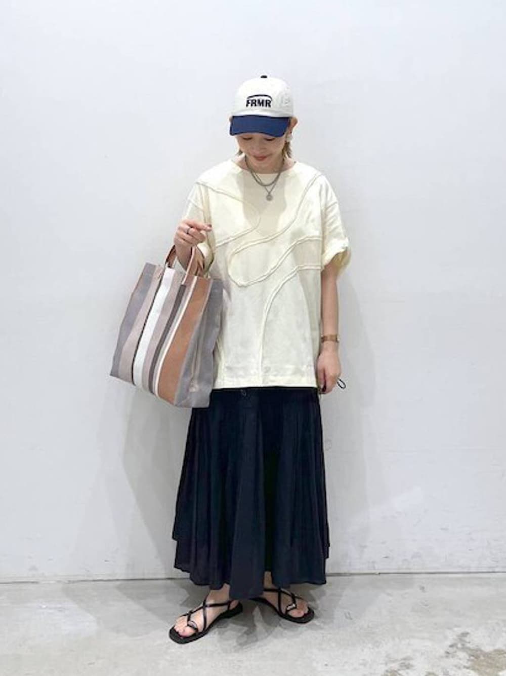 ブラック系のスカート、ブラック系のサンダル、グリーン系のTシャツ/カットソーを着用したレディースの春コーディネートの1枚目の写真