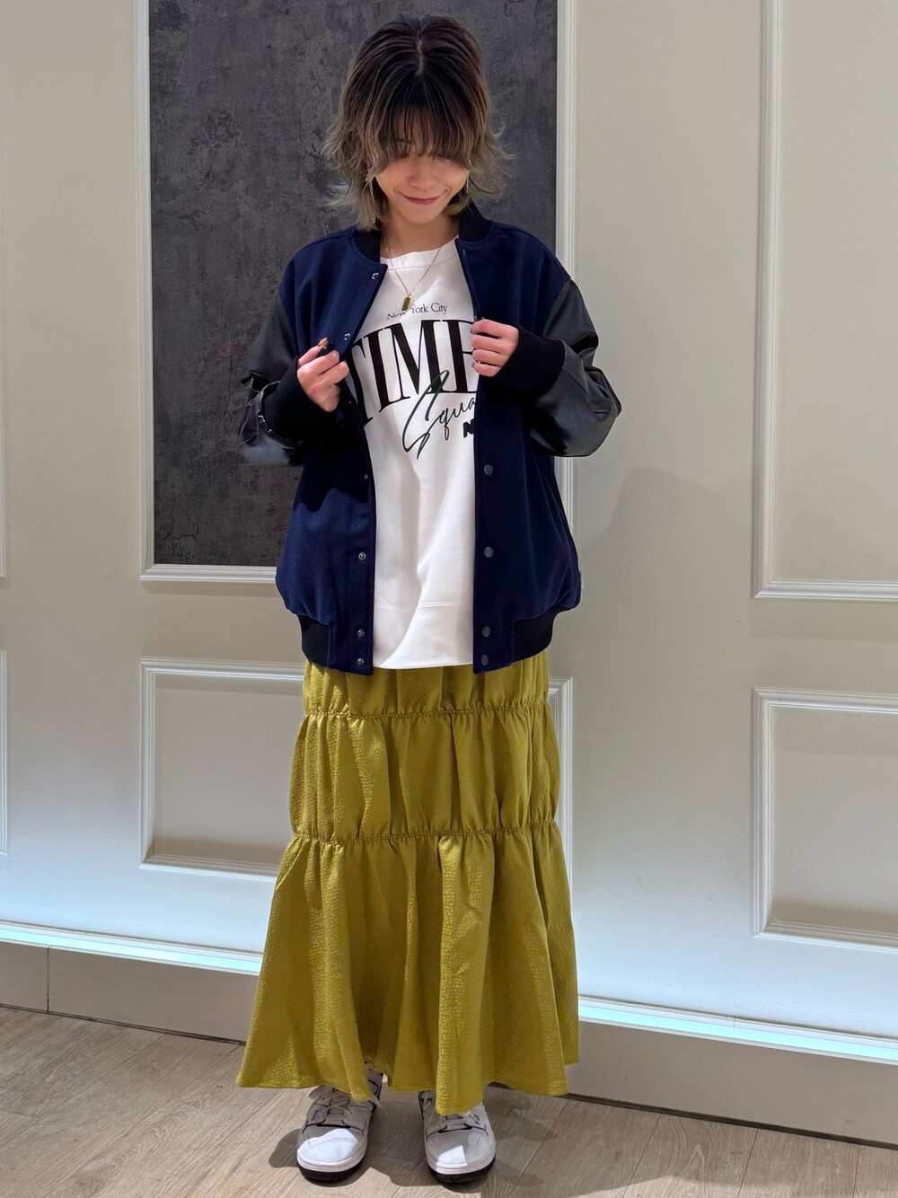 ブルー系のスタジャン、ホワイト系のスウェット、イエロー系のスカートを着用したレディースの秋コーディネートの1枚目の写真