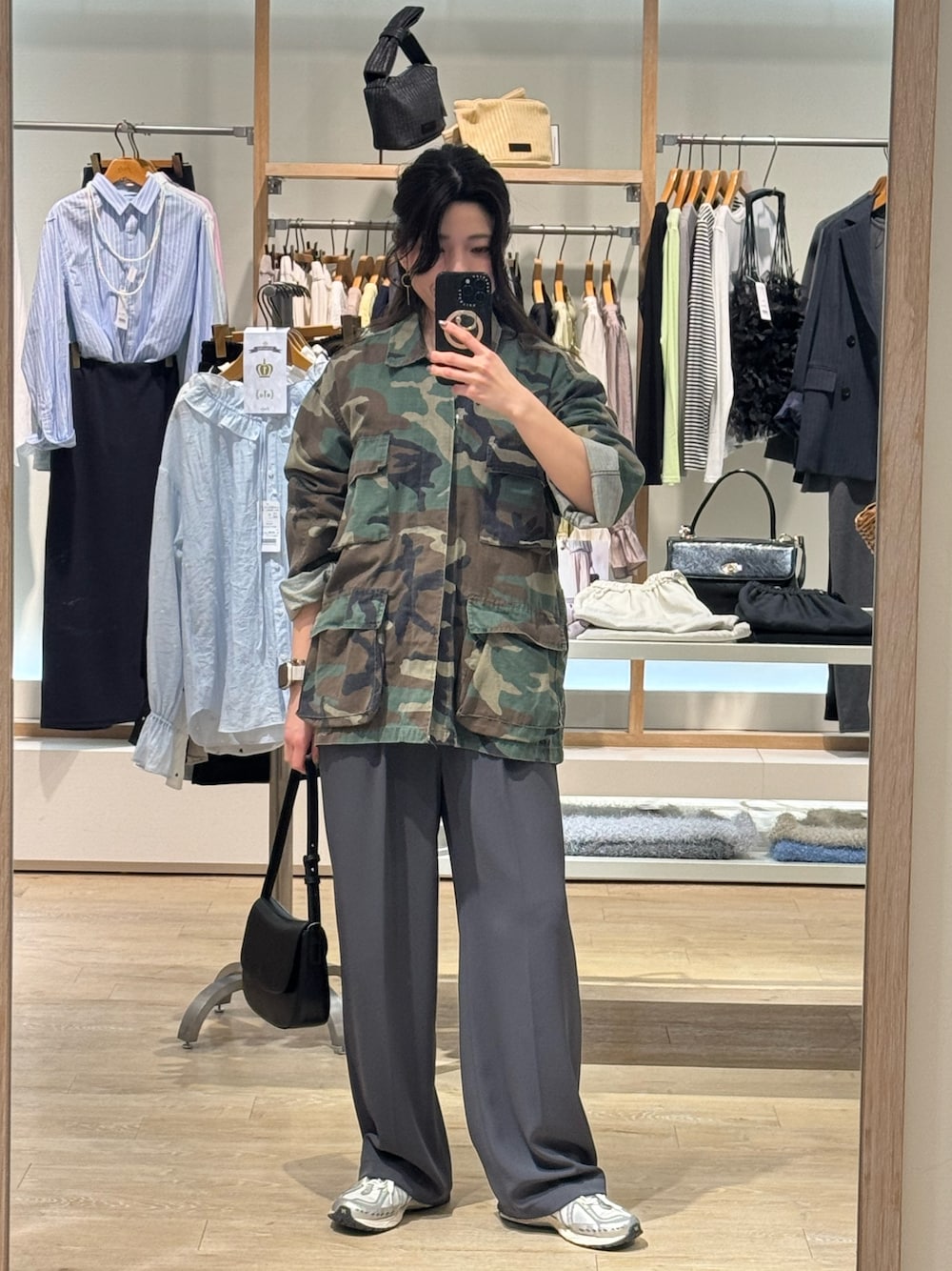 ブラウン系のミリタリージャケット、グレー系のスラックス、ブラック系のショルダーバッグを着用したレディースの春コーディネートの1枚目の写真