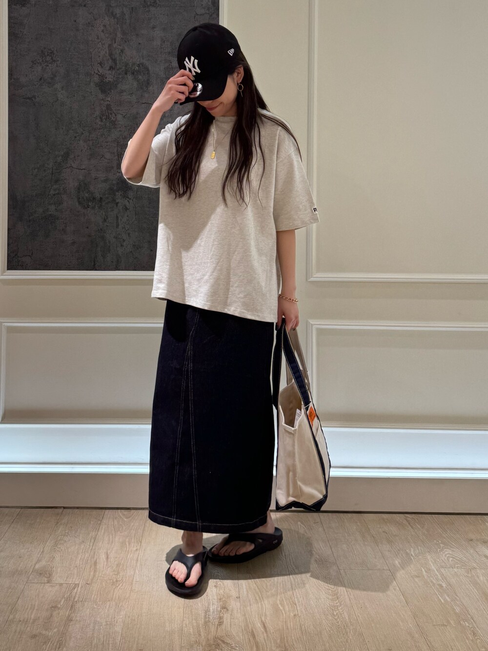 ベージュ系のTシャツ/カットソー、ブルー系のデニムスカート、ブラック系のトートバッグを着用したレディースの春コーディネートの1枚目の写真