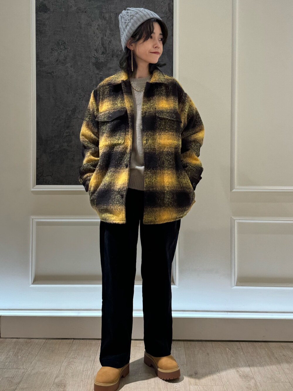 イエロー系のブルゾン、ブラック系のその他パンツ、ベージュ系のニット/セーターを着用したレディースの秋コーディネートの1枚目の写真