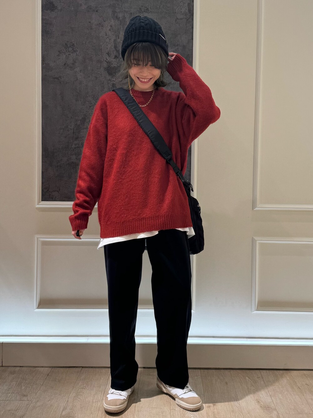 レッド系のニット/セーター、ブラック系のショルダーバッグ、ブラック系のスラックスを着用したレディースの冬コーディネートの1枚目の写真