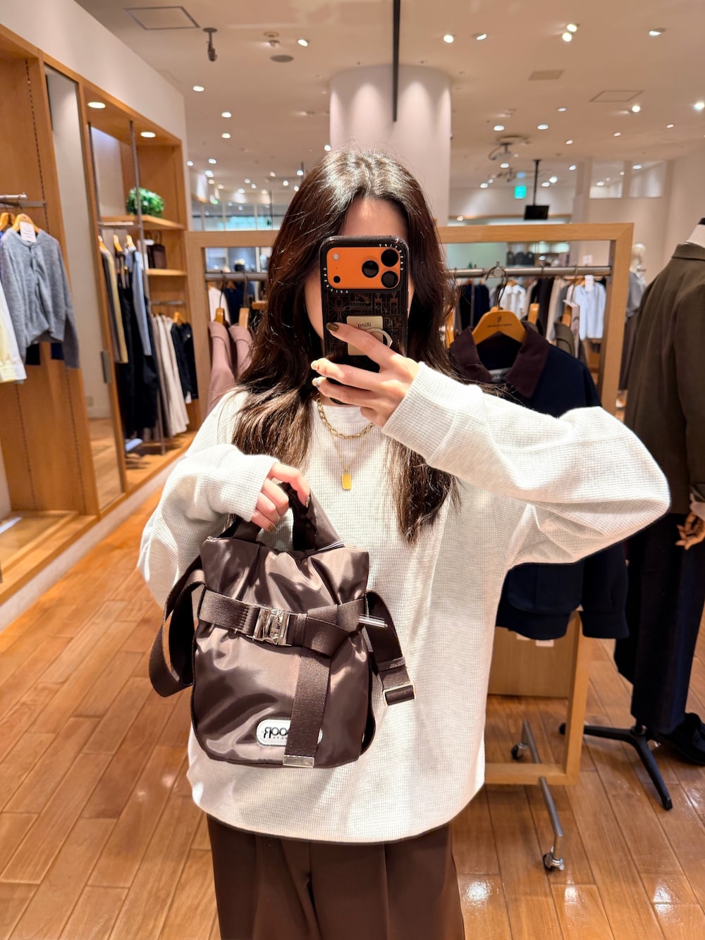 グレー系のTシャツ/カットソー、ブラウン系のショルダーバッグ、ブラウン系のスラックスを着用したレディースの秋コーディネートの1枚目の写真