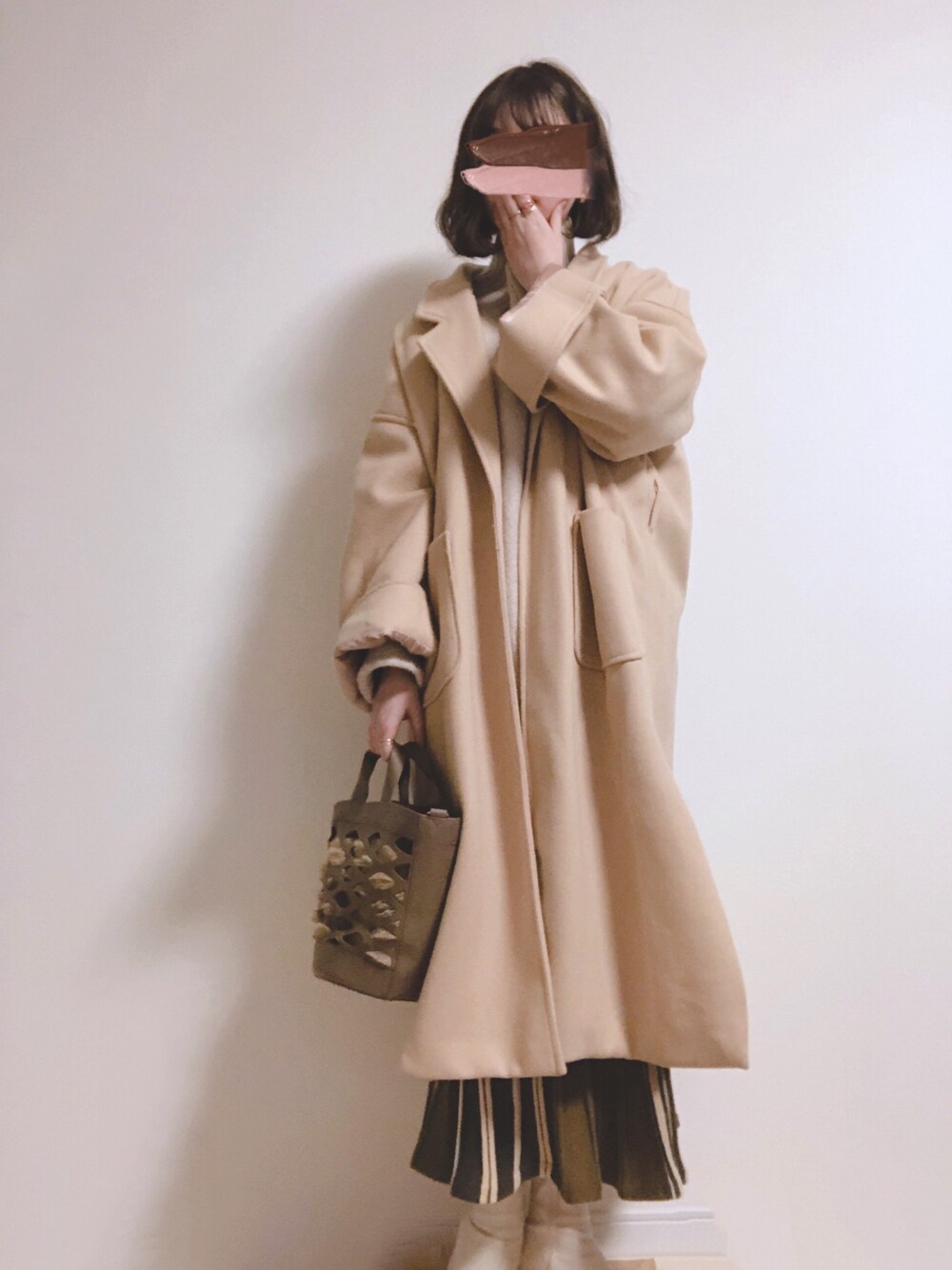 ベージュ系のニット/セーター、ベージュ系のチェスターコート、ブラウン系のバッグを着用したレディースの冬コーディネートの1枚目の写真