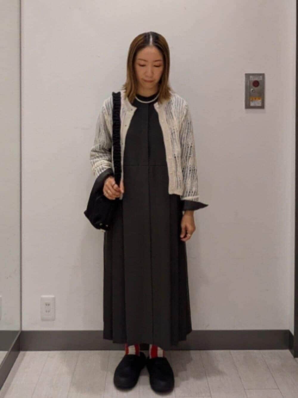 グレー系のワンピース、ブラック系のショルダーバッグ、ホワイト系のカーディガン/ボレロを着用したレディースの秋コーディネートの1枚目の写真