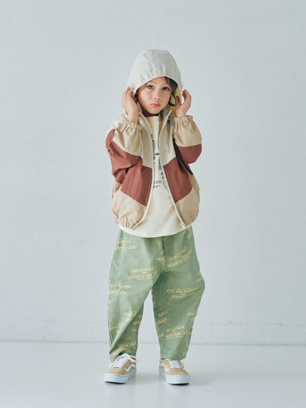 ベージュ系のナイロンジャケット、ホワイト系のTシャツ/カットソー、グリーン系のその他パンツを着用したキッズの冬コーディネートの1枚目の写真