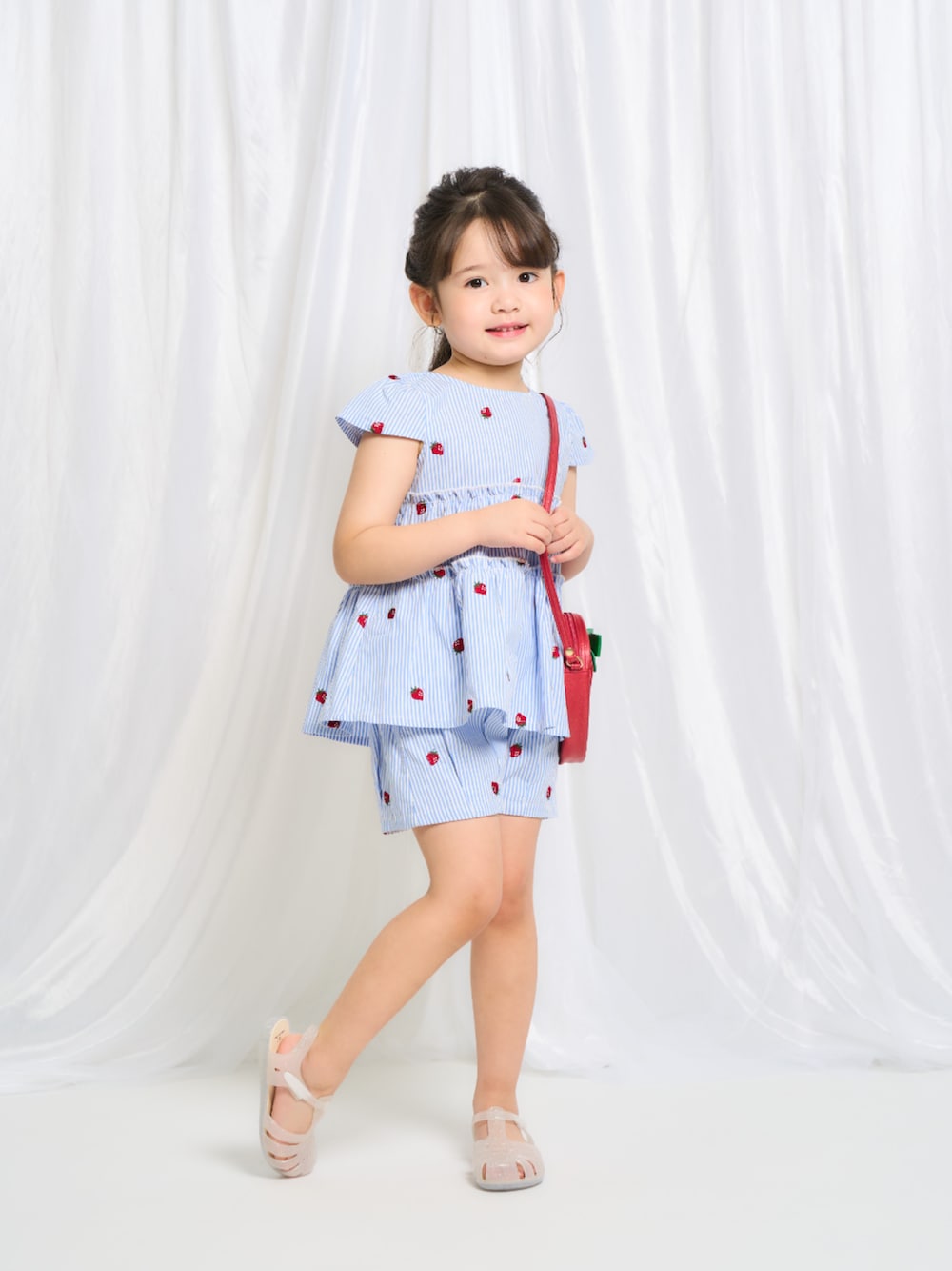 「F.O.Online Store、エフオーオンラインストア(F.O.Online Store)、apres les cours、アプレレクール、キッズファッション、キッズコーデ、女の子、セットアップ、ハーフパンツ、サンダル、ショルダーバッグ、お出かけコーデ、春夏コーデ、淡色コーデ、ストライプ」｜「apres les coursのいちごモチーフポシェット（ショルダーバッグ、レッド系）」を使った、F.O.OnlineStoreさん（キッズ・110cm）の春コーディネートの1枚目の写真