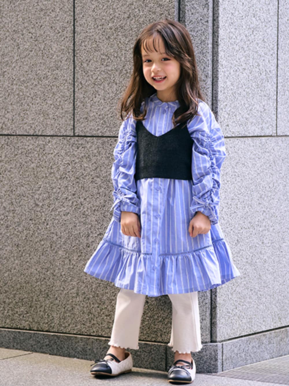 「エフオーオンラインストア(F.O.Online Store)、F.O.Online Store、apres les cours、ワンピース、春ワンピ、ストライプ、ブルー、おんなのこ、ベスト×ワンピース、カジュアル、着回しコーデ、キッズコーデ、春コーデ、おでかけコーデ、ワンピーススタイル」｜「apres les coursの後ろリボンニットビスチェ（ベスト、ブラック系）」を使った、F.O.OnlineStoreさん（キッズ・110cm）の冬コーディネートの1枚目の写真