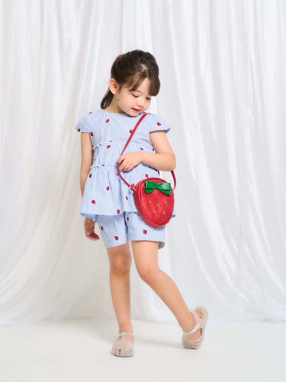 「F.O.Online Store、エフオーオンラインストア(F.O.Online Store)、apres les cours、アプレレクール、キッズコーデ、キッズファッション、女の子、女の子コーデ、きれいめカジュアル、トートバッグ、ショルダーバッグ、セットアップ、ストライプ、サンダル、お出かけコーデ」｜「apres les coursのいちごモチーフポシェット（ショルダーバッグ、レッド系）」を使った、F.O.OnlineStoreさん（キッズ・110cm）の夏コーディネートの1枚目の写真
