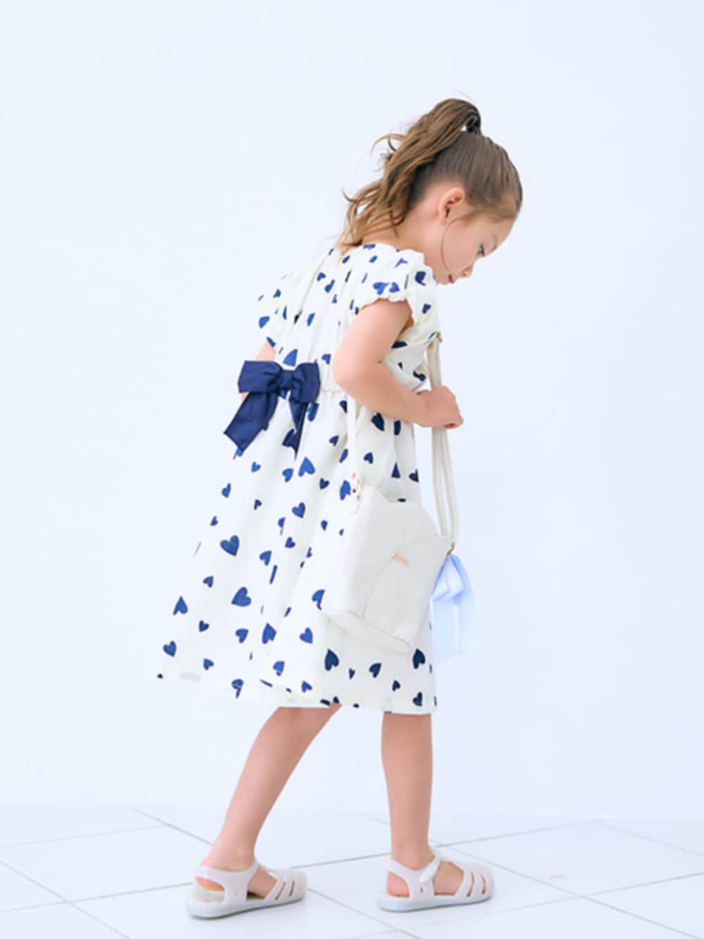 「F.O.Online Store、エフオーオンラインストア(F.O.Online Store)、apres les cours、アプレレクール、ワンピース、ハート柄、リボン、夏ワンピース、夏ワンピ、キッズコーデ、キッズファッション、女の子、カジュアル、カジュアルガーリー、お出かけコーデ」｜「apres les coursの【リンク】バックリボンヒロインワンピ（ワンピース、ホワイト系）」を使った、F.O.OnlineStoreさん（キッズ・110cm）の夏コーディネートの1枚目の写真