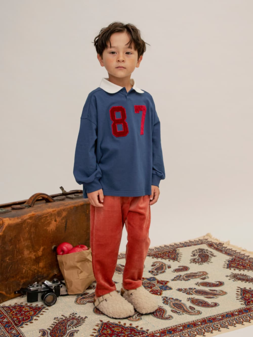 ブルー系のポロシャツ、ホワイト系のサンダル、レッド系のその他パンツを着用したキッズの冬コーディネートの1枚目の写真