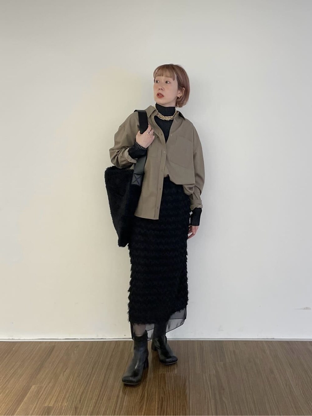ベージュ系のシャツ/ブラウス、ブラック系のニット/セーター、ブラック系のスカートを着用したレディースの冬コーディネートの1枚目の写真