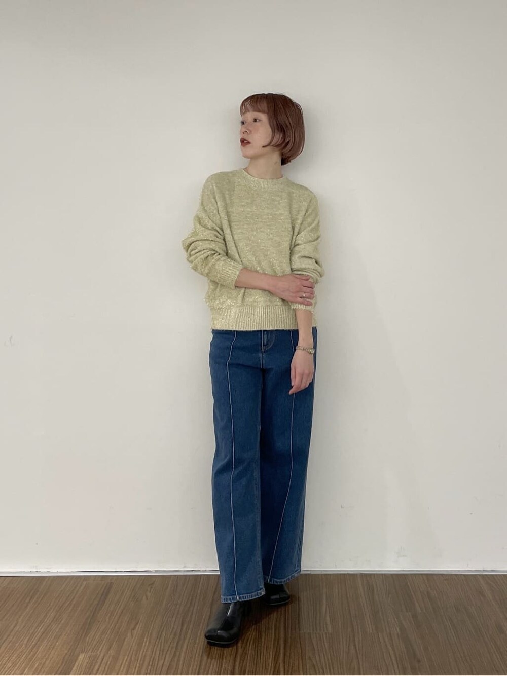 ブルー系のデニムパンツ、ゴールド系のニット/セーターを着用したレディースの秋コーディネートの1枚目の写真