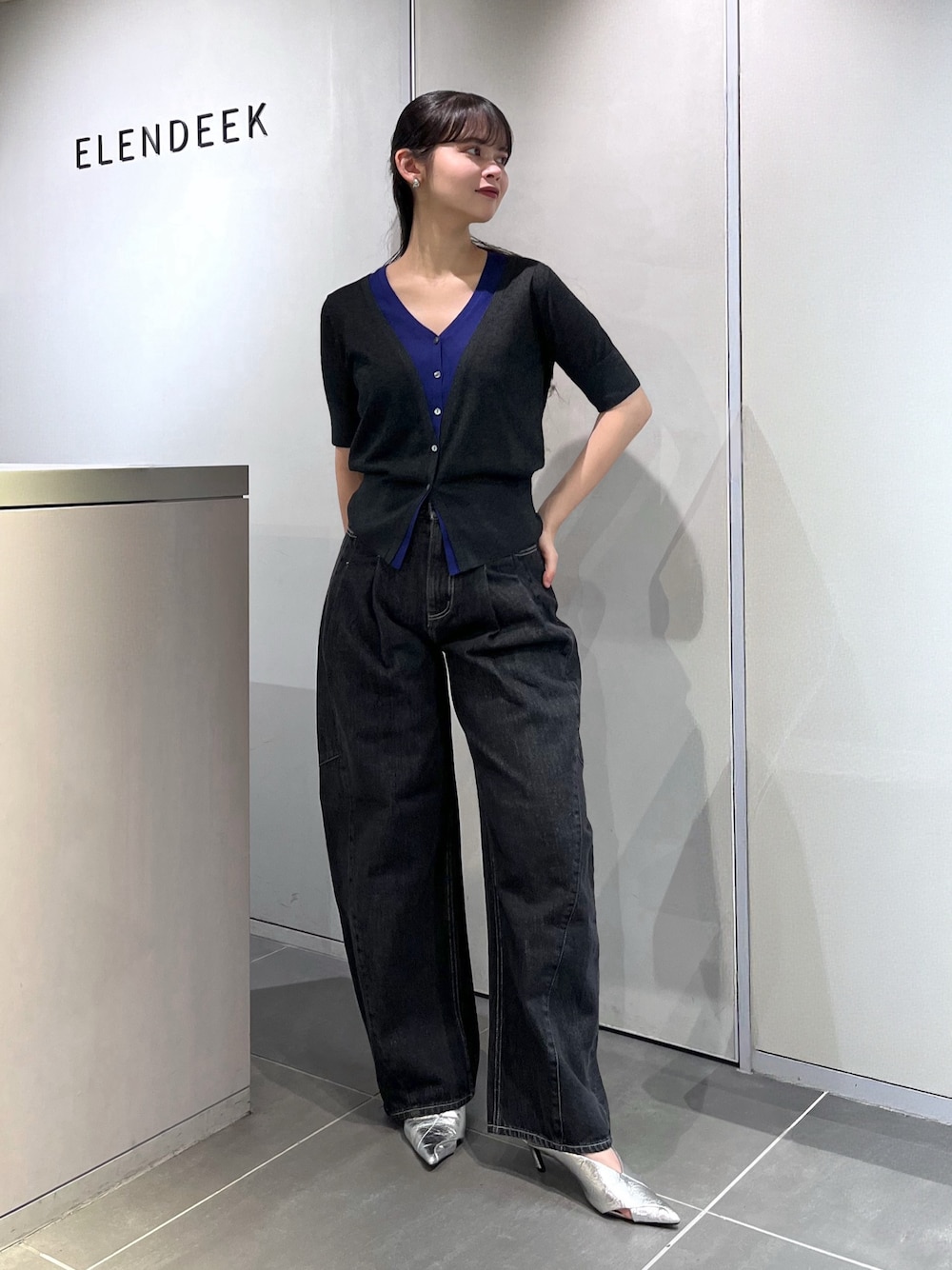 グレー系のニット/セーター、ブラック系のデニムパンツ、シルバー系のパンプスを着用したレディースの夏コーディネートの1枚目の写真