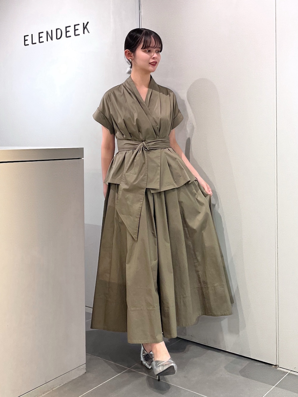 シルバー系のパンプス、グリーン系のワンピース、シルバー系のシュシュを着用したレディースの夏コーディネートの1枚目の写真