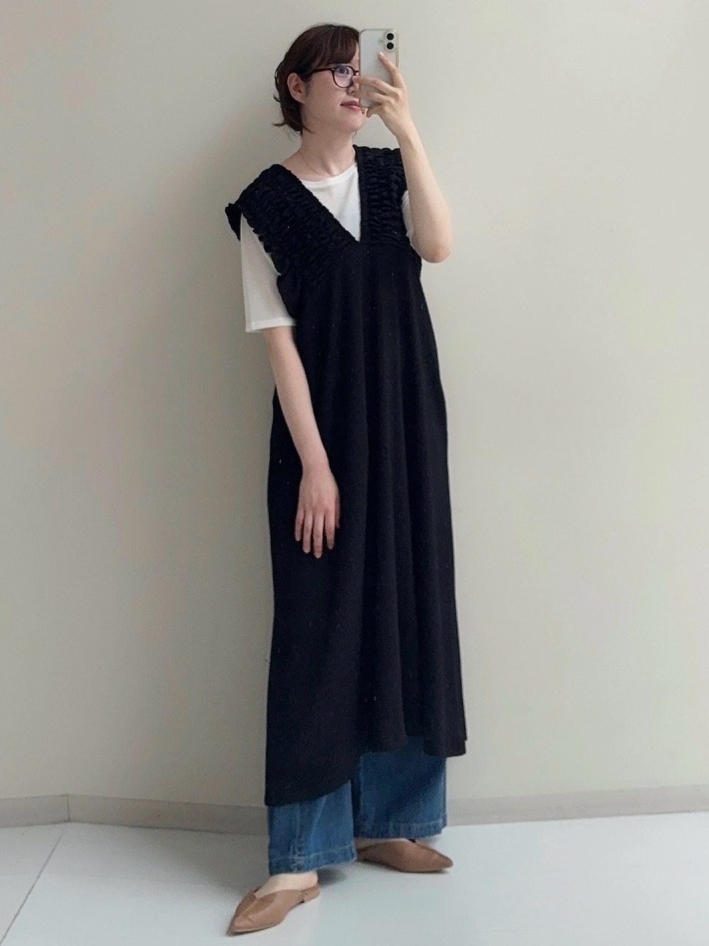 ブラック系のジャンパースカート、ブルー系のデニムパンツ、ホワイト系のTシャツ/カットソーを着用したレディースの春コーディネートの1枚目の写真