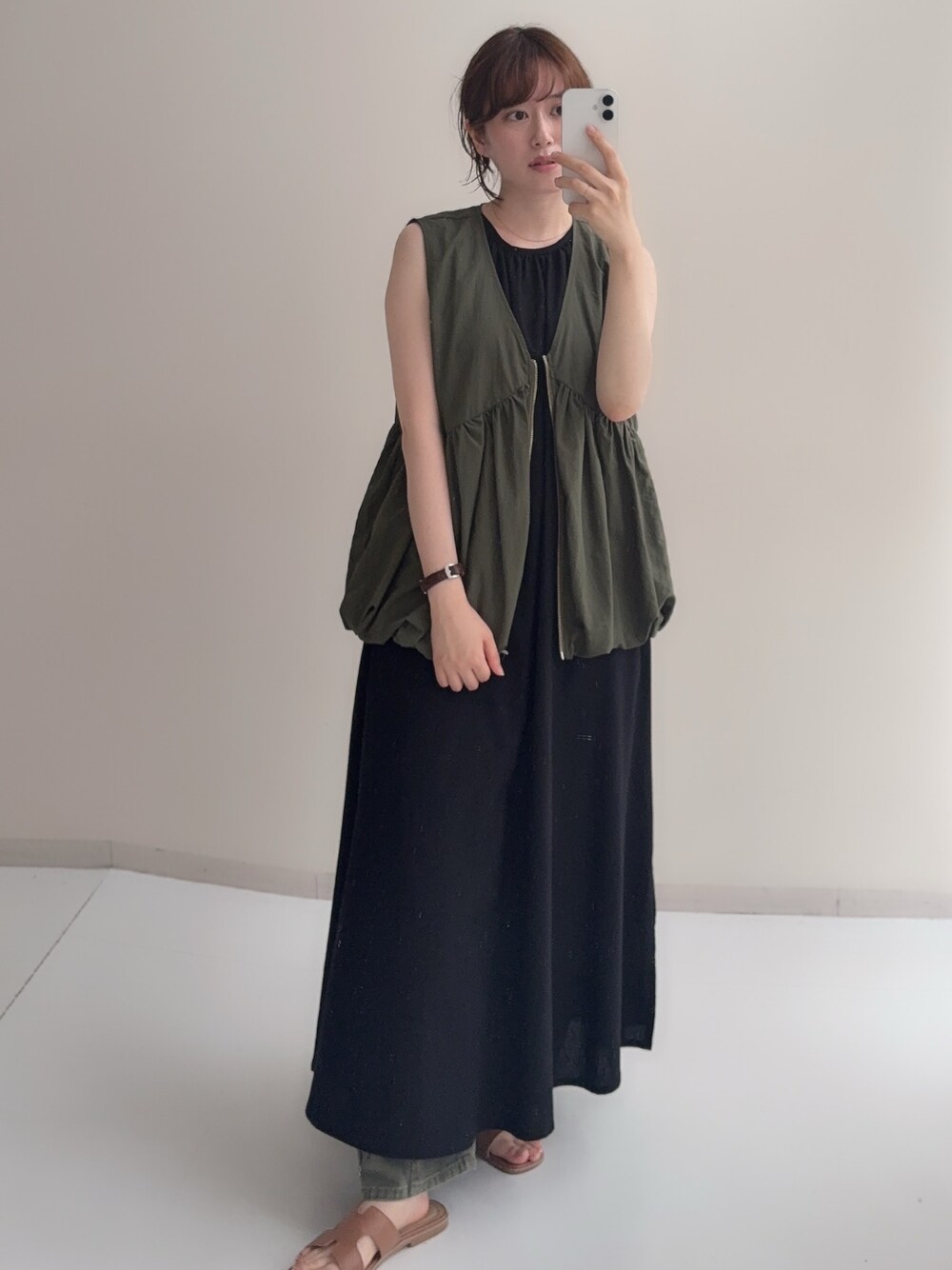 ブラック系のワンピース、ブラウン系のベスト、ベージュ系のデニムパンツを着用したレディースの夏コーディネートの1枚目の写真