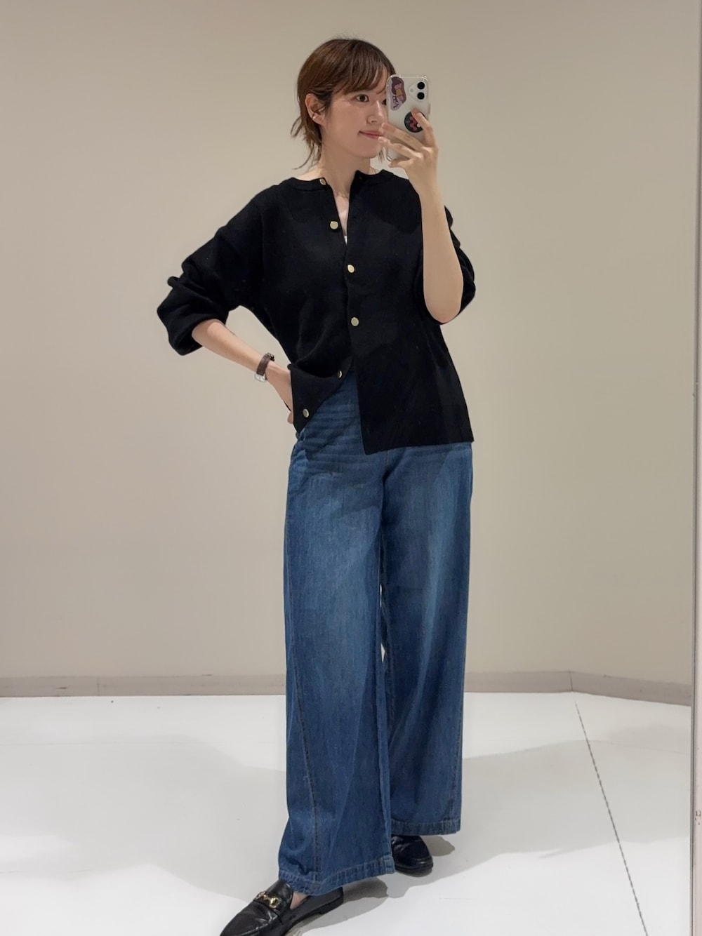 ブルー系のデニムパンツ、ブラック系のカーディガン/ボレロを着用したレディースの秋コーディネートの1枚目の写真