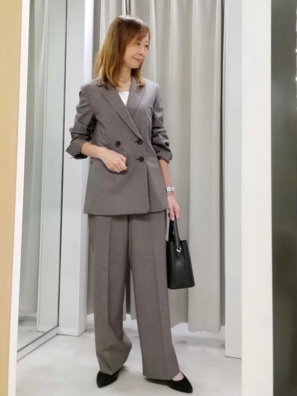 ベージュ系のテーラードジャケット、ベージュ系のその他パンツ、ホワイト系のタンクトップを着用したレディースの秋コーディネートの1枚目の写真