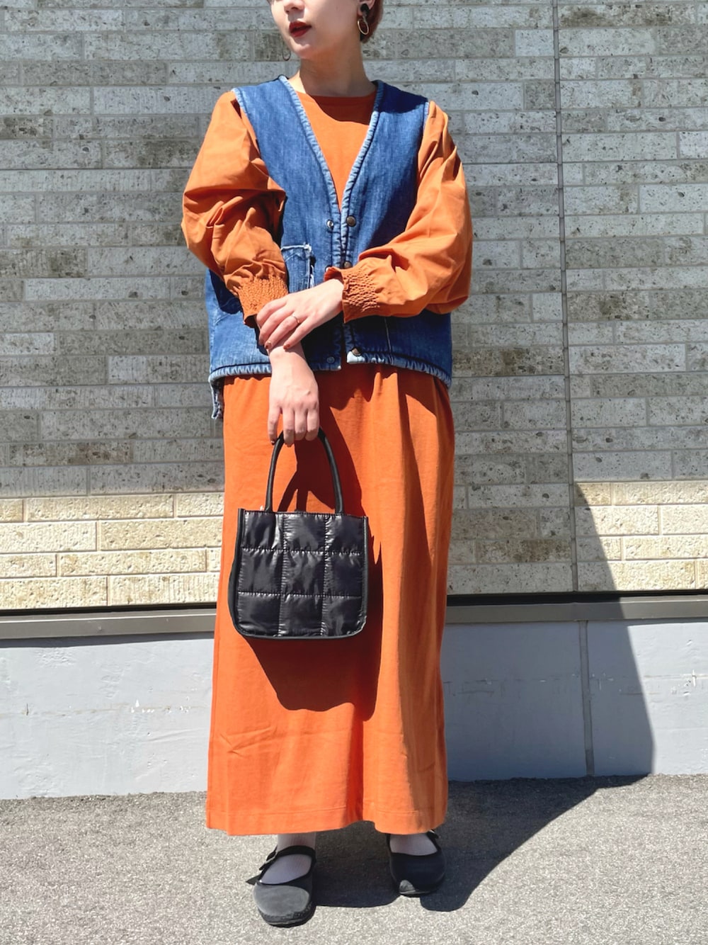 レッド系のワンピース、ブラック系のショルダーバッグ、グレー系のシューズを着用したレディースの秋コーディネートの1枚目の写真