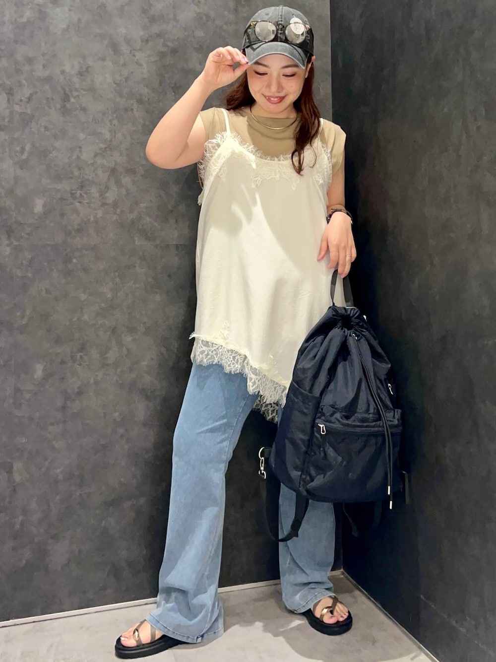 ベージュ系のTシャツ/カットソー、ブラウン系のサンダル、ブラック系のバックパック/リュックを着用したレディースの夏コーディネートの1枚目の写真