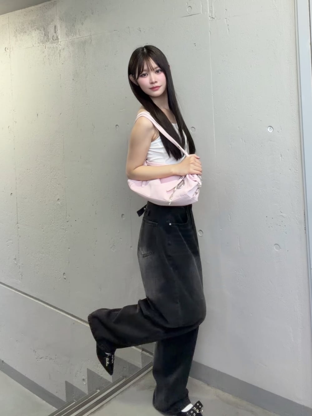 ブラック系のデニムパンツ、ピンク系のショルダーバッグ、ホワイト系のキャミソールを着用したレディースの秋コーディネートの1枚目の写真