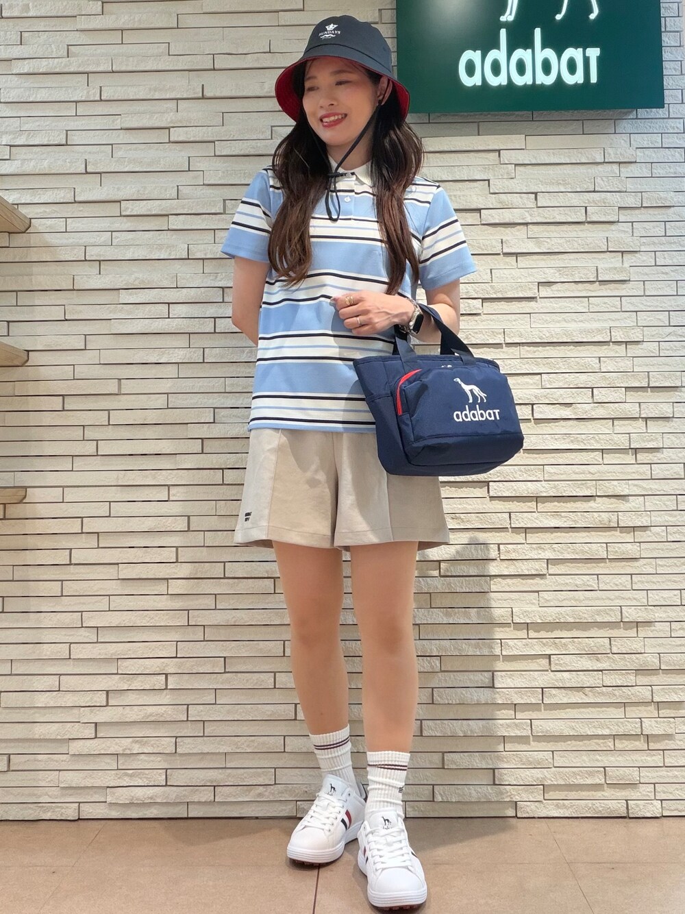 ブルー系のポロシャツ、ベージュ系のその他パンツ、ブルー系のトートバッグを着用したレディースの夏コーディネートの1枚目の写真
