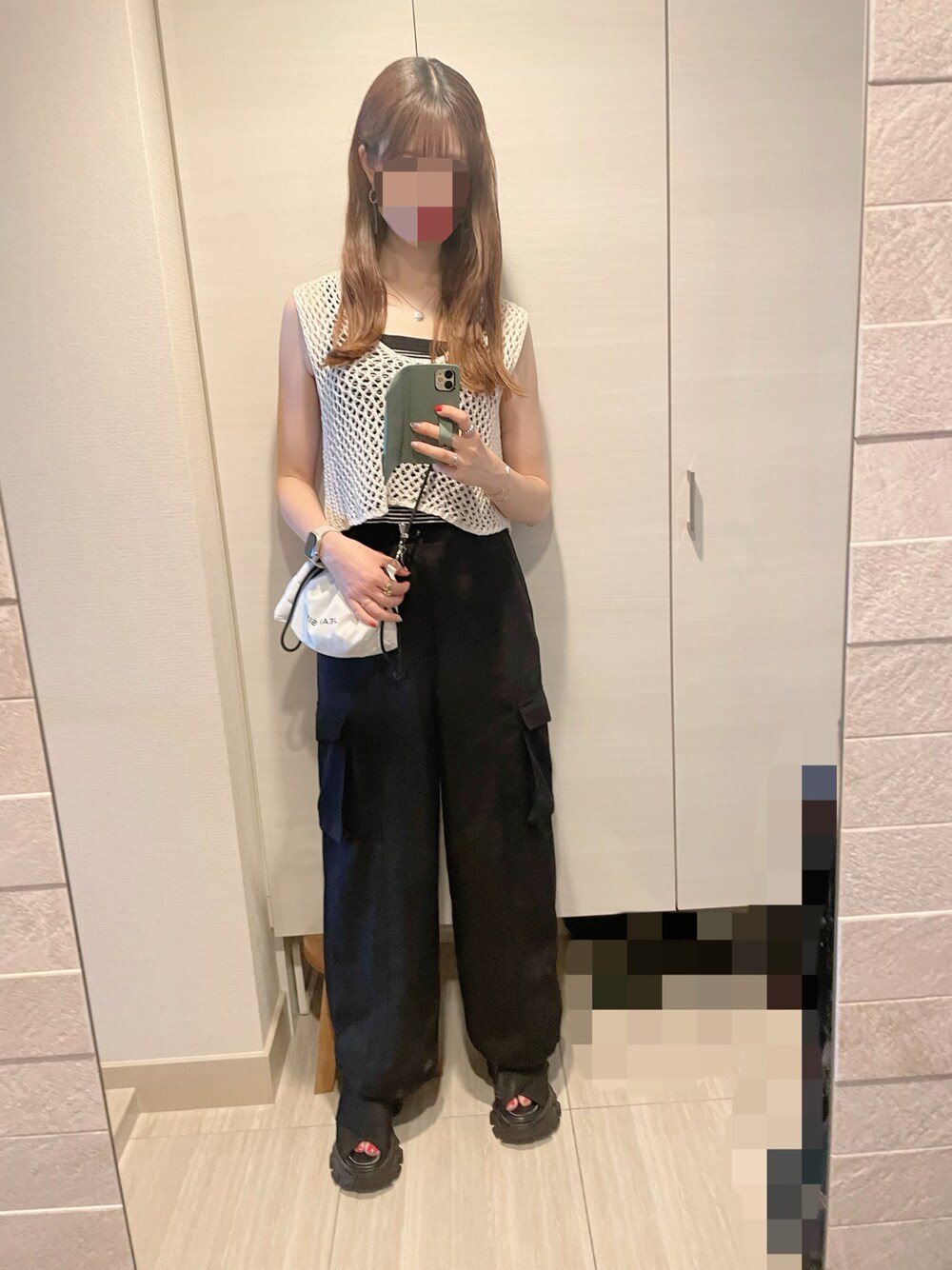 ブラック系のカーゴパンツ、ブラック系のサンダル、ホワイト系のバッグを着用したレディースの夏コーディネートの1枚目の写真