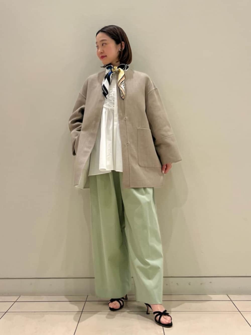 ベージュ系のノーカラーコート、ホワイト系のシャツ/ブラウス、グリーン系のその他パンツを着用したレディースの春コーディネートの1枚目の写真