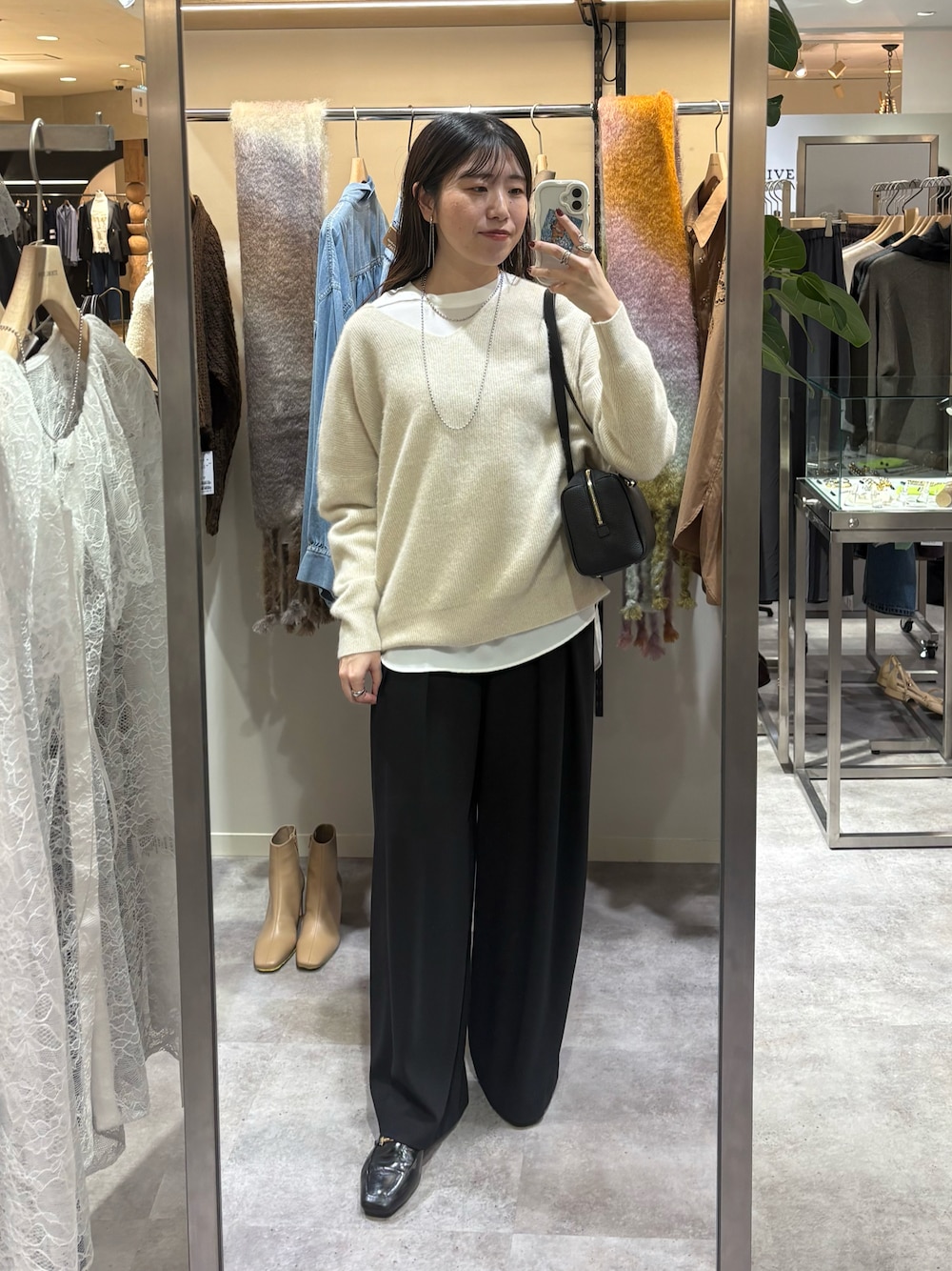 ベージュ系のニット/セーター、ホワイト系のシャツ/ブラウス、ブラック系のスラックスを着用したレディースの秋コーディネートの1枚目の写真