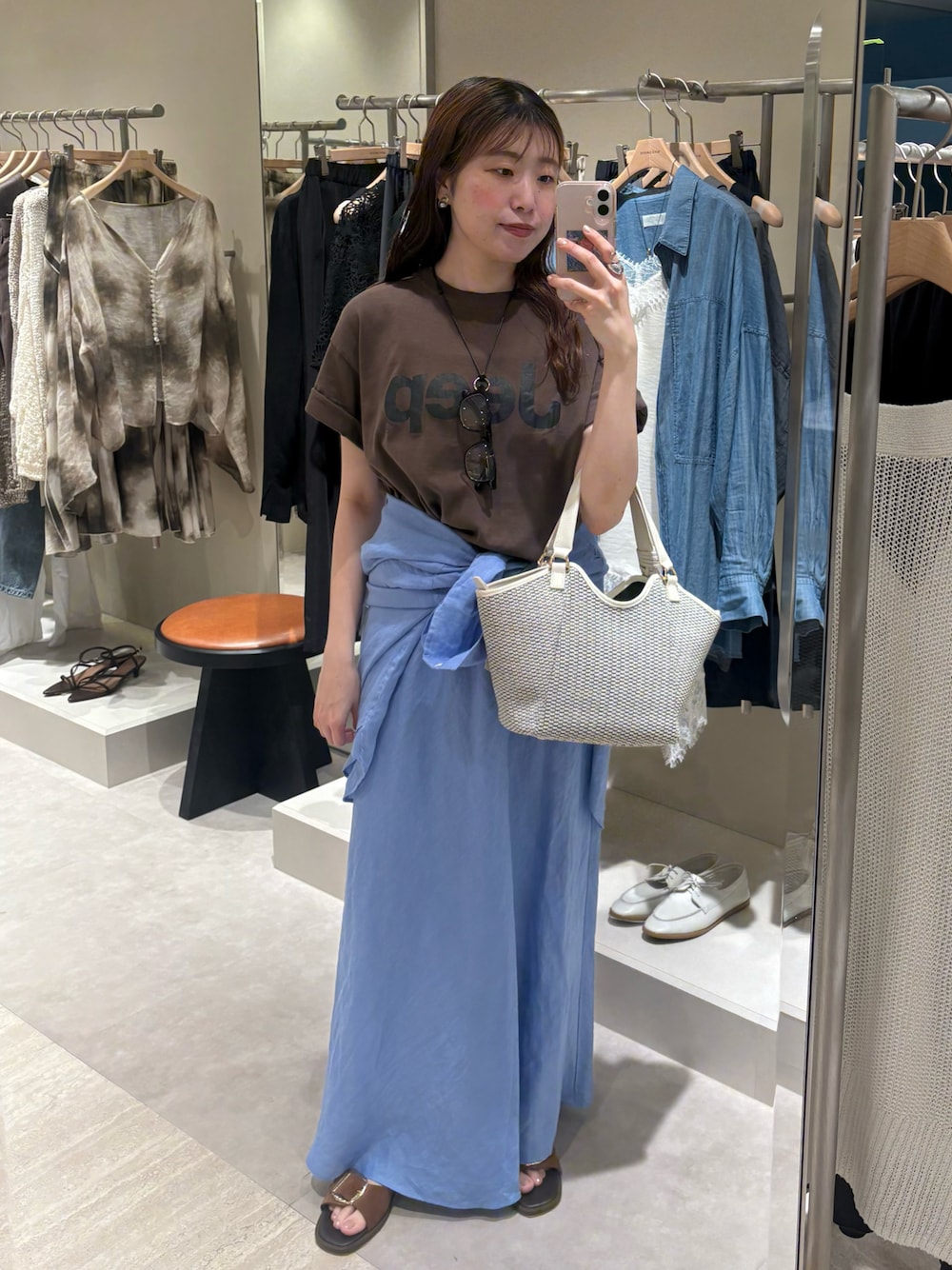 ブラウン系のTシャツ/カットソー、ホワイト系のハンドバッグ、ブルー系のスカートを着用したレディースの夏コーディネートの1枚目の写真