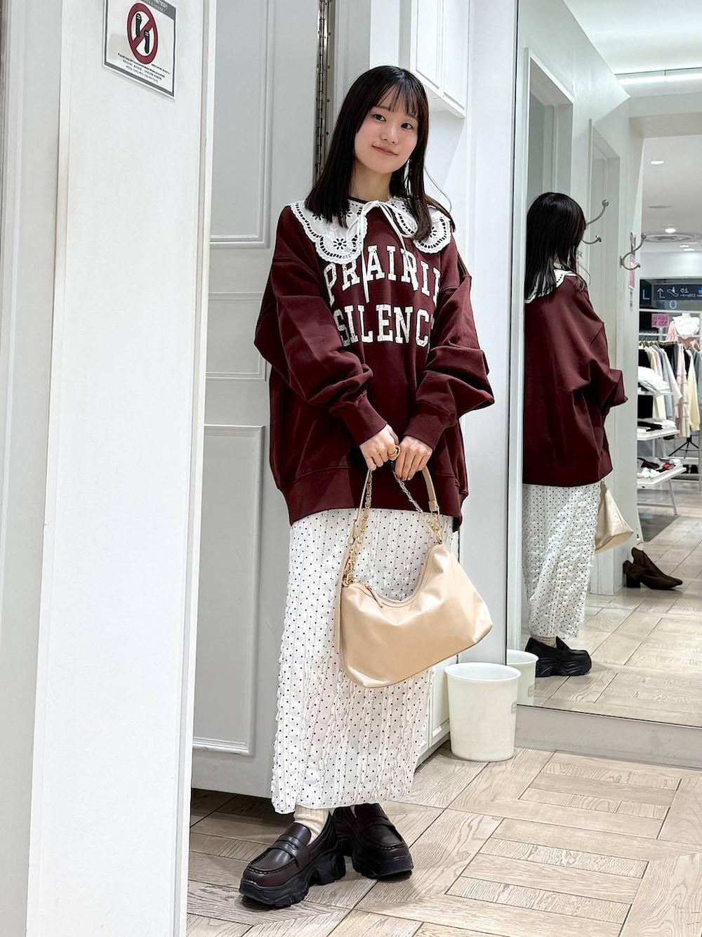 ベージュ系のショルダーバッグ、ブラウン系のローファー、ホワイト系のスカートを着用したレディースの冬コーディネートの1枚目の写真