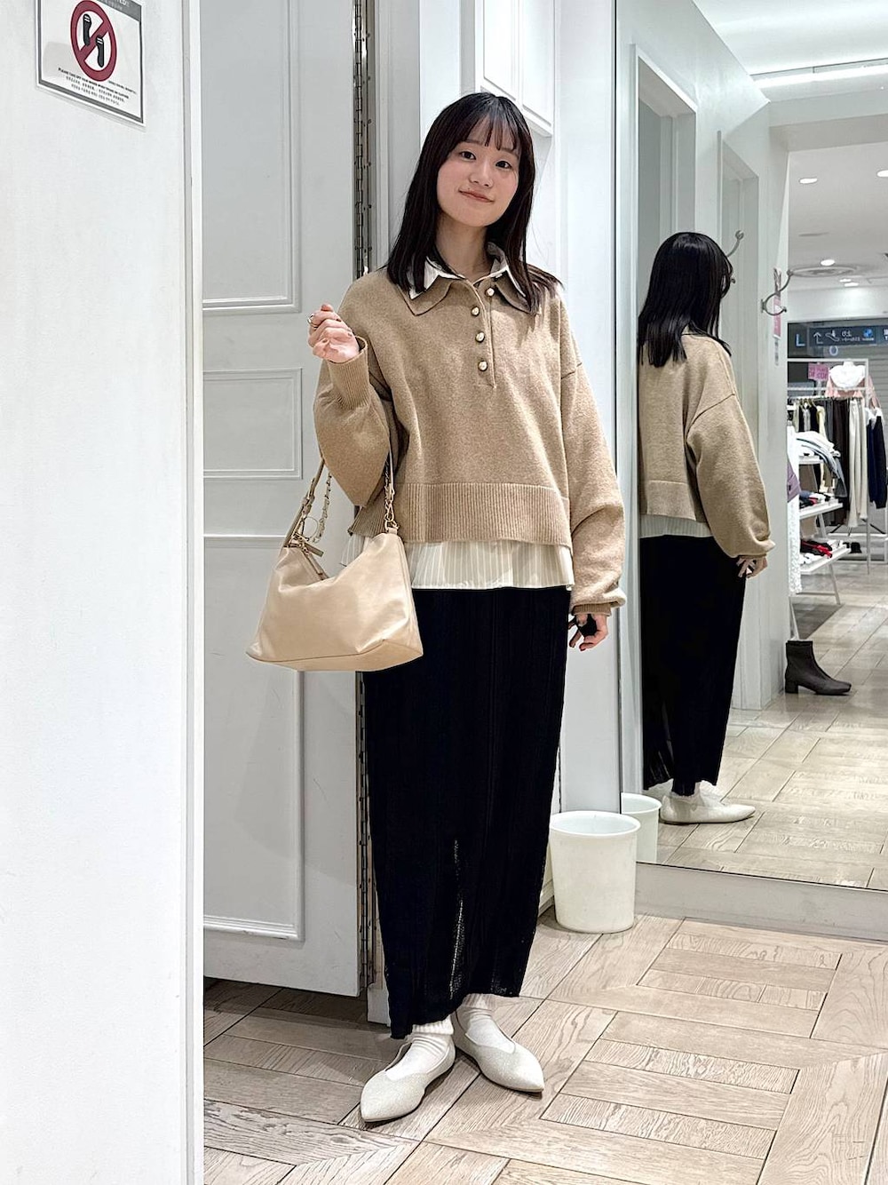 ベージュ系のショルダーバッグ、ホワイト系のパンプス、ブラック系のスカートを着用したレディースの冬コーディネートの1枚目の写真