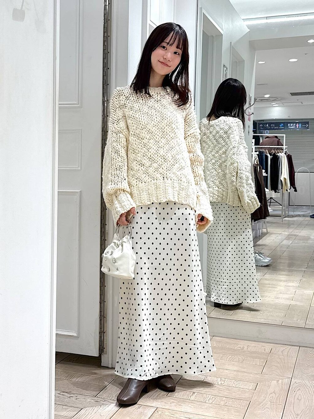 ホワイト系のスカート、ホワイト系のニット/セーター、ホワイト系のハンドバッグを着用したレディースの冬コーディネートの1枚目の写真