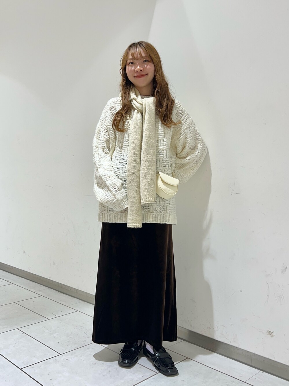ホワイト系のニット/セーター、ホワイト系のショルダーバッグ、ブラウン系のスカートを着用したレディースの秋コーディネートの1枚目の写真