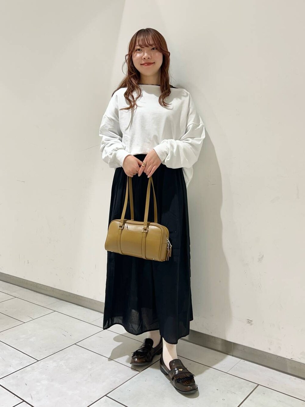 グリーン系のボストンバッグ、ブラック系のスカート、ブラック系のTシャツ/カットソーを着用したレディースの冬コーディネートの1枚目の写真