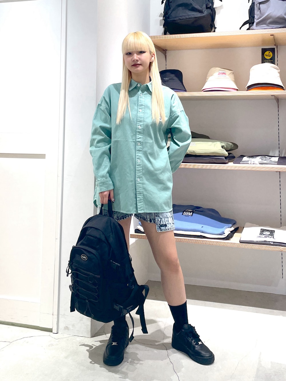 グリーン系のシャツ/ブラウス、ブラック系のバックパック/リュック、ブルー系のデニムパンツを着用したレディースの春コーディネートの1枚目の写真