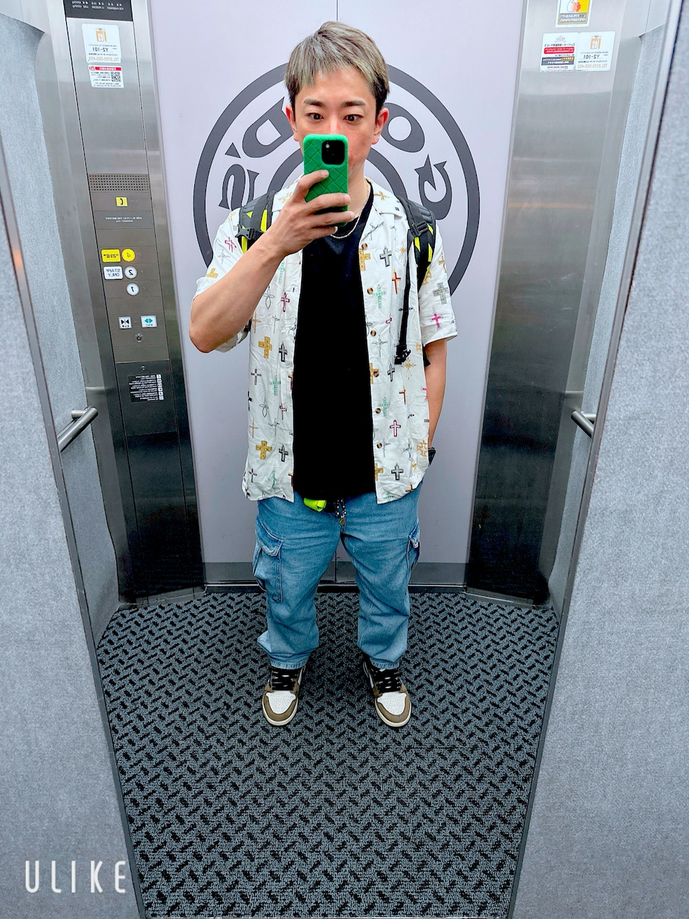 ブルー系のデニムパンツ、ブラウン系のスニーカー、ブラック系のタンクトップを着用したメンズの春コーディネートの1枚目の写真