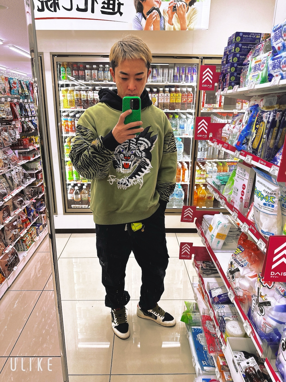 グリーン系のパーカー、グリーン系のスニーカー、ブラック系のカーゴパンツを着用したメンズの春コーディネートの1枚目の写真