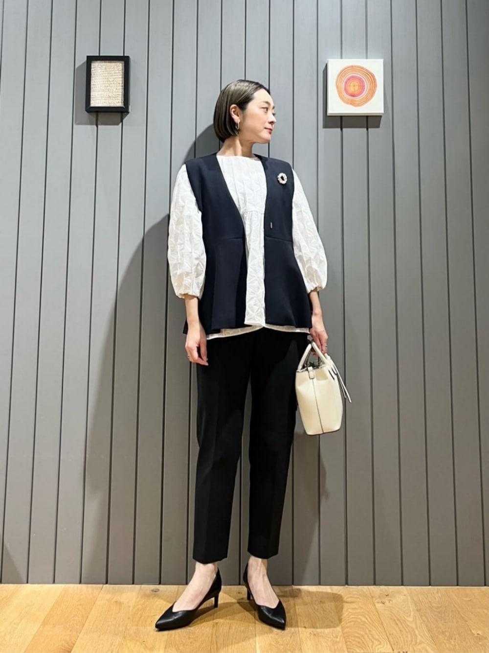 ブルー系のベスト、ホワイト系のシャツ/ブラウス、ブラック系のスラックスを着用したレディースの冬コーディネートの1枚目の写真