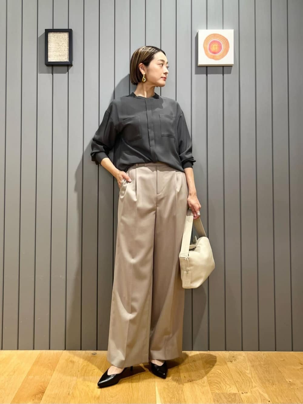 ブラック系のパンプス、ホワイト系のショルダーバッグ、グレー系のシャツ/ブラウスを着用したレディースの秋コーディネートの1枚目の写真