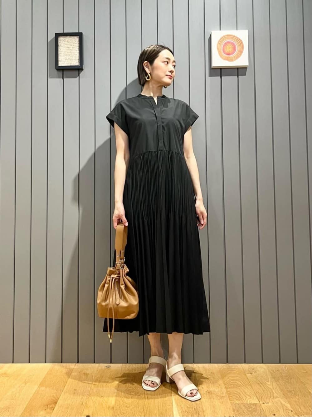 ホワイト系のサンダル、ブラック系のワンピース、ブラウン系のショルダーバッグを着用したレディースの夏コーディネートの1枚目の写真