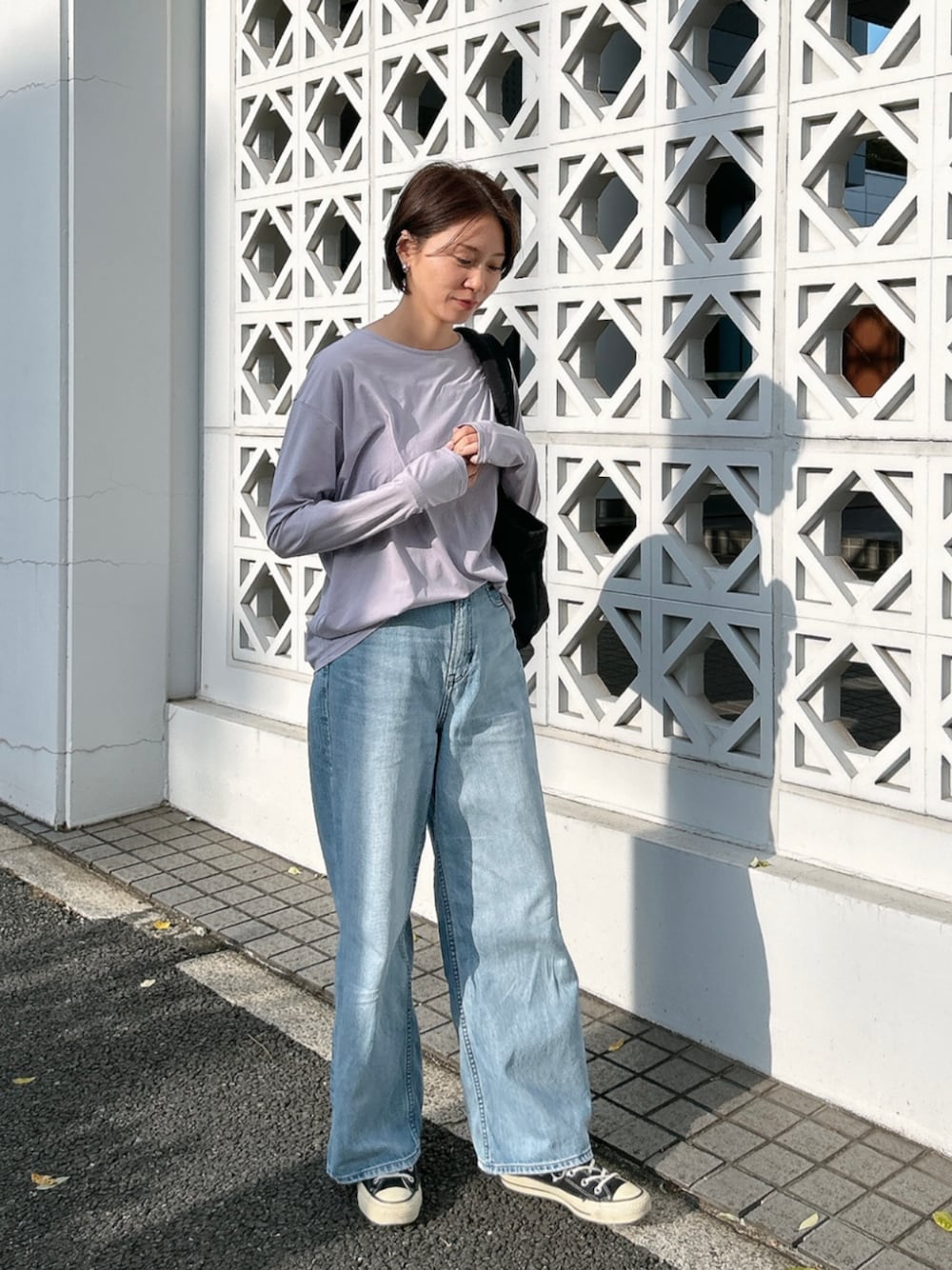 ブラック系のトートバッグ、パープル系のTシャツ/カットソーを着用したレディースの春コーディネートの1枚目の写真