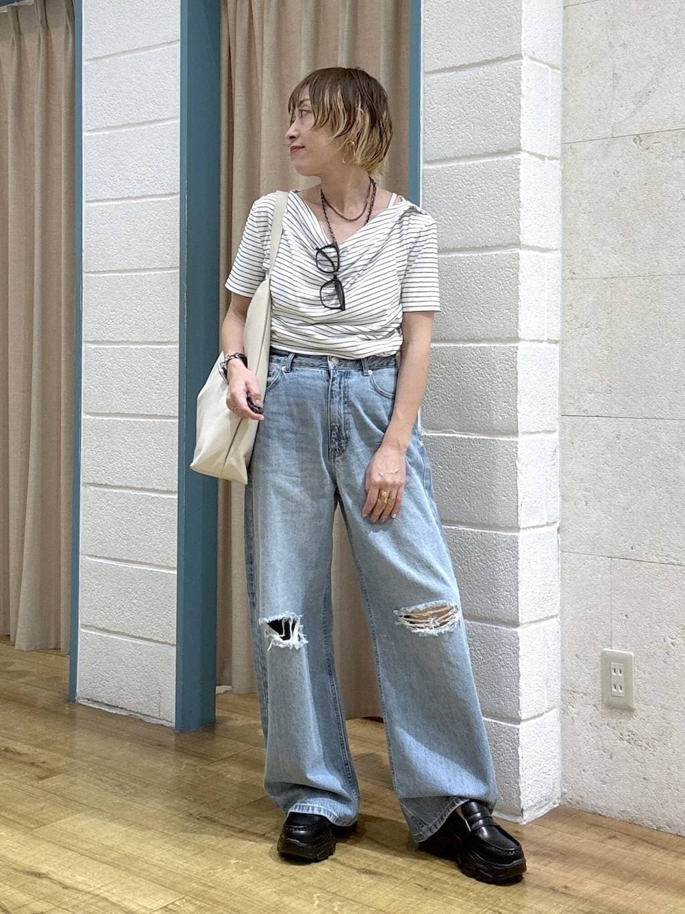 ブルー系のデニムパンツ、ブラック系のローファー、ホワイト系のショルダーバッグを着用したレディースの春コーディネートの1枚目の写真