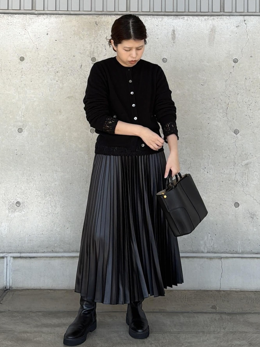 ブラック系のハンドバッグ、ブラック系のカーディガン/ボレロ、ブラック系のTシャツ/カットソーを着用したレディースの秋コーディネートの1枚目の写真