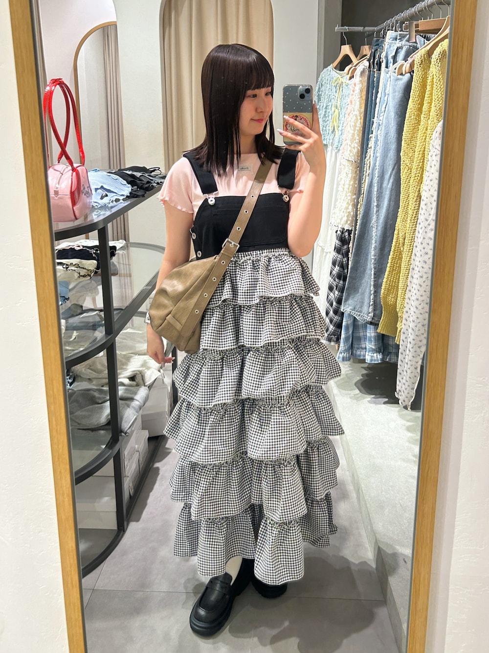 ピンク系のTシャツ/カットソー、ブラウン系のトートバッグ、ブラック系のジャンパースカートを着用したレディースの春コーディネートの1枚目の写真