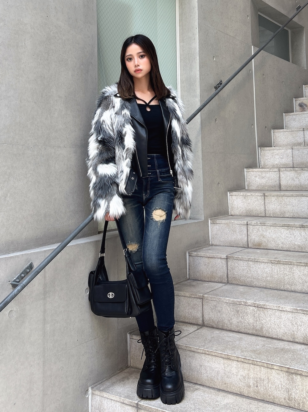 ブルー系のデニムパンツ、ブラック系のブーツ、ブラウン系のハンドバッグを着用したレディースの秋コーディネートの1枚目の写真