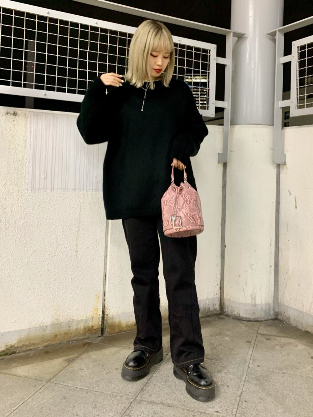 ピンク系のショルダーバッグ、ブラック系のデニムパンツ、ブラック系のニット/セーターを着用したレディースの冬コーディネートの1枚目の写真